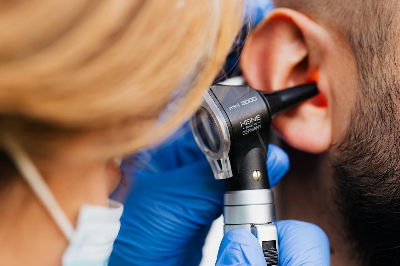 hero A medical professional examines a patient's ear using a Heine otoscope, highlighting healthcare quality.